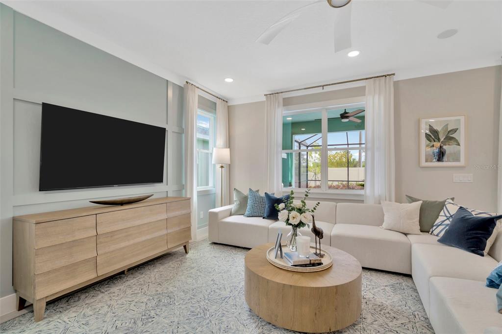 A living room features a light wood media console, sectional sofa, and a round coffee table — 3892 ROCKY ISLAND ROAD, NEW PORT RICHEY, FL