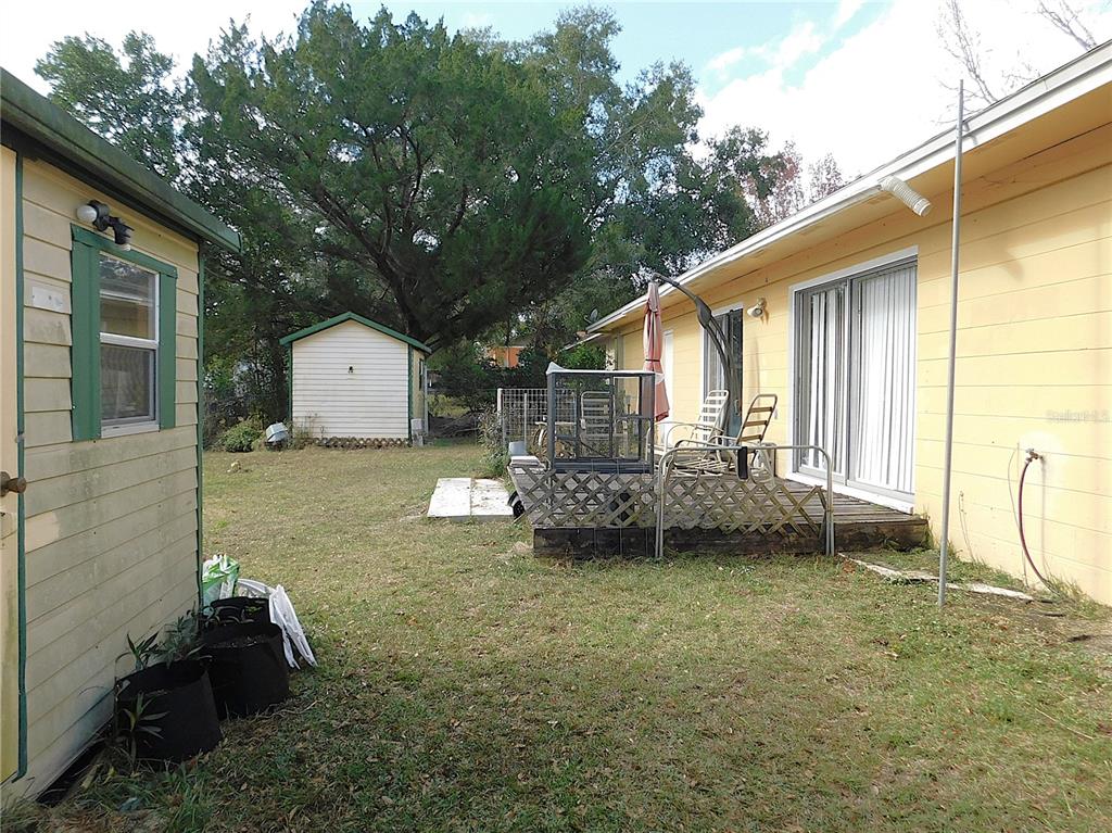 A backyard view showing a small shed, a wooden deck, and the side of a house — 3610 SW 150TH LANE ROAD, OCALA, FL