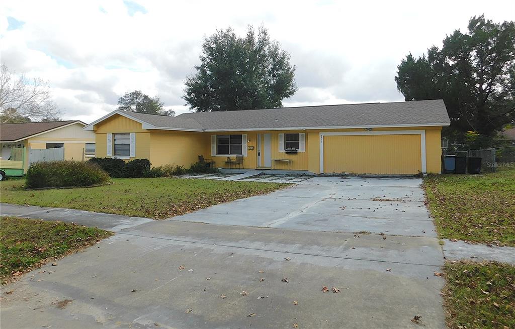 A yellow single-story house features a concrete driveway, a two-car garage, and a front lawn — 3610 SW 150TH LANE ROAD, OCALA, FL