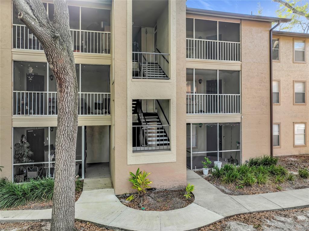 An exterior view of a three-story apartment building with screened-in balconies and outdoor staircases — 615 DORY LANE UNIT 303, ALTAMONTE SPRINGS, FL