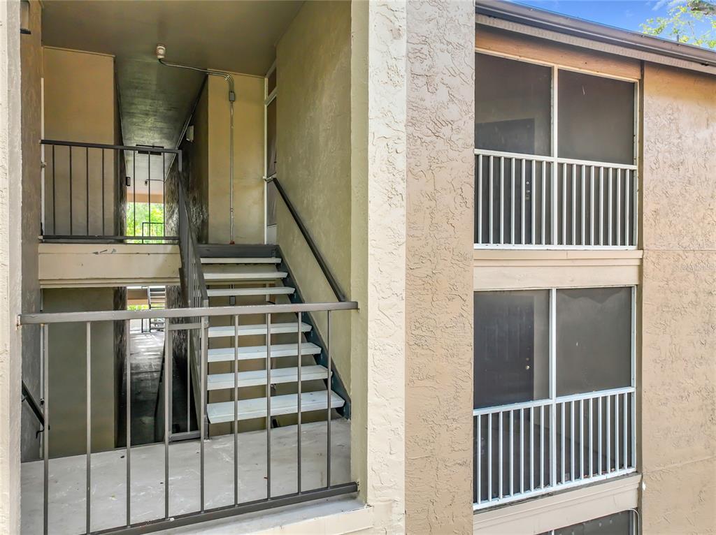 An exterior view of a two-story apartment building with concrete stairs and metal railings — 615 DORY LANE UNIT 303, ALTAMONTE SPRINGS, FL