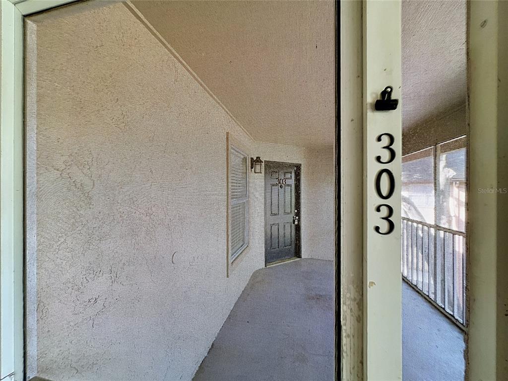 A covered outdoor walkway leads to a dark entry door labeled with the number 303 — 615 DORY LANE UNIT 303, ALTAMONTE SPRINGS, FL