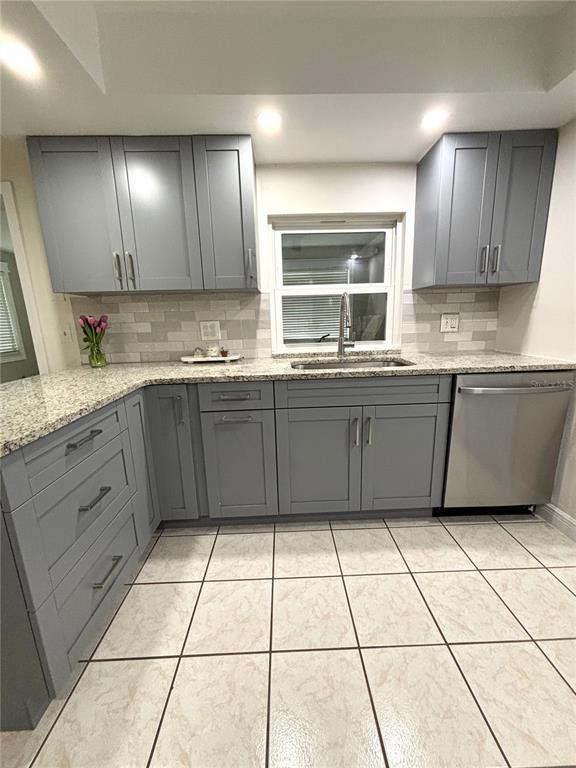 A kitchen features gray cabinets, granite countertops, a tiled backsplash, and light-colored floor tiles — 1707 IRONWOOD COURT E, OLDSMAR, FL
