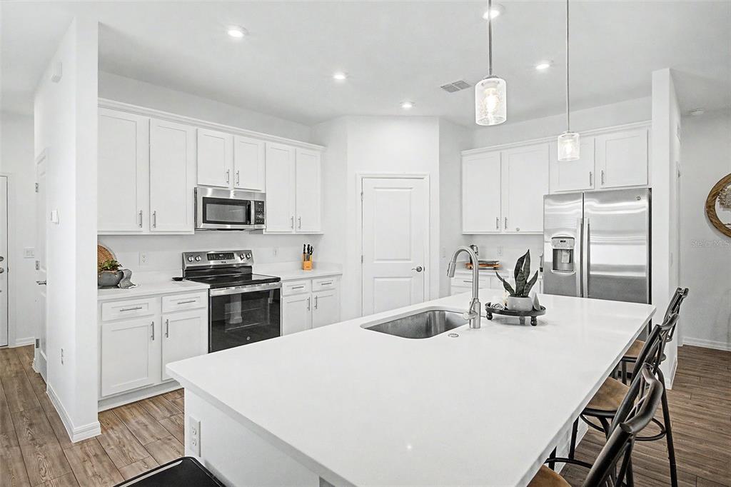 A modern kitchen features white cabinets, stainless steel appliances, and a large central island — 703 ROCKAWAY LANE, COCOA, FL