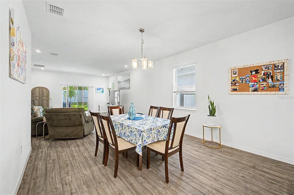 A dining area with a floral tablecloth, wooden chairs, and a corkboard on the wall — 703 ROCKAWAY LANE, COCOA, FL