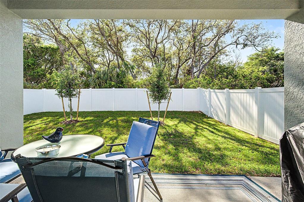 A covered patio overlooks a small grassy backyard enclosed by a white vinyl privacy fence — 703 ROCKAWAY LANE, COCOA, FL