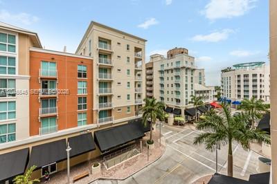 An elevated view shows multi-story apartment buildings with balconies and ground-level storefronts near a street — 7285 SW 90th St # D409, Miami FL 33156, MIAMI, FL