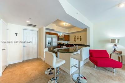 A kitchen with a breakfast bar and two white stools sits next to a red sofa — 7285 SW 90th St # D409, Miami FL 33156, MIAMI, FL