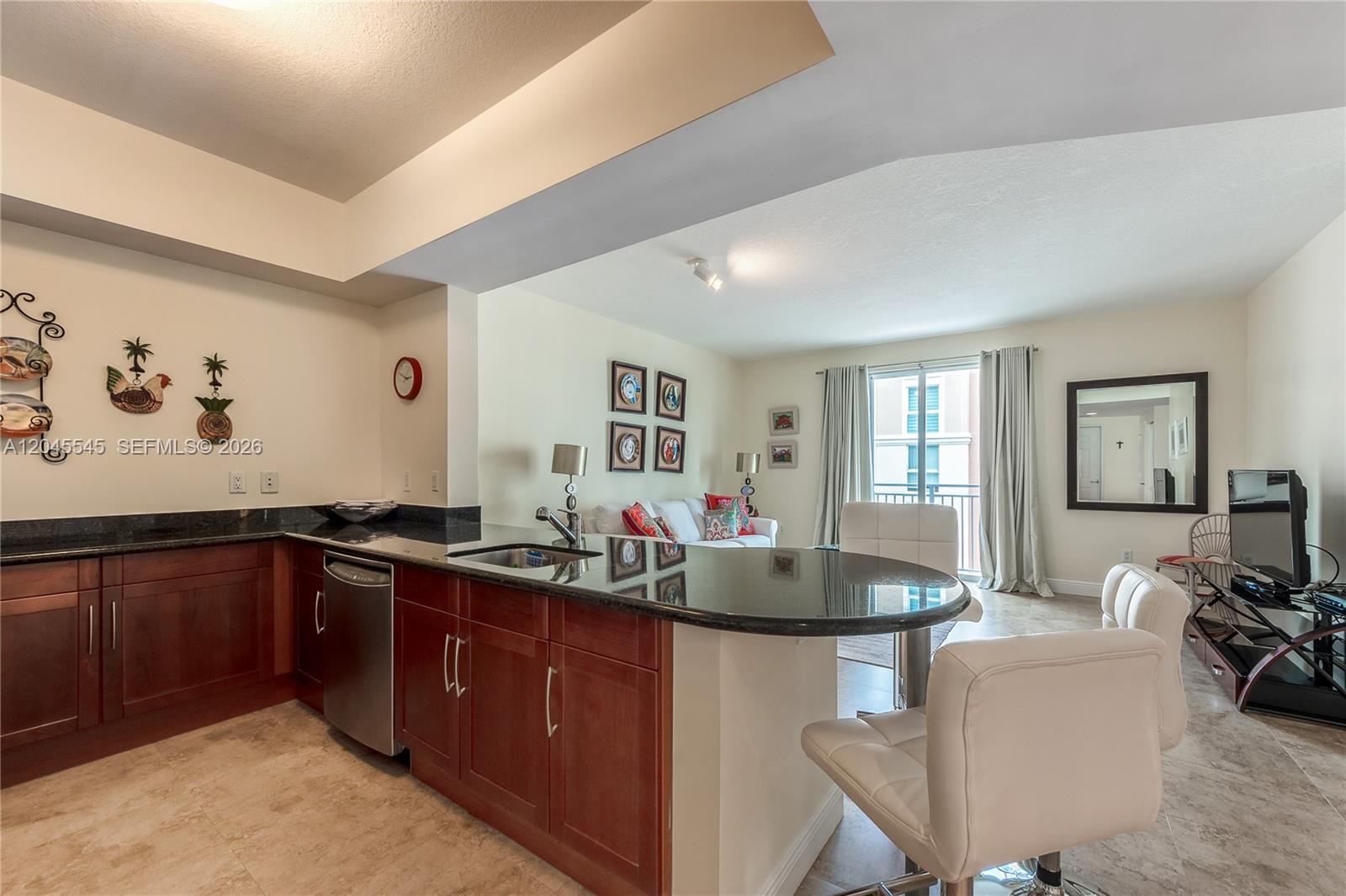 A kitchen with dark wood cabinets and granite countertops opens into a living area — 7285 SW 90th St # D409, Miami FL 33156, MIAMI, FL