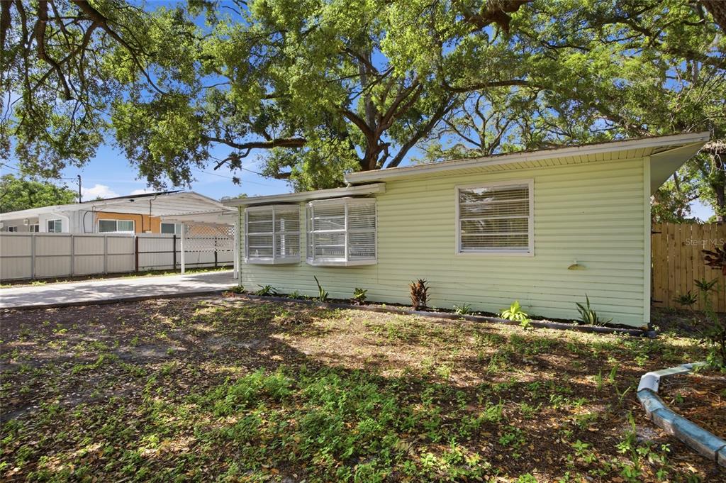 The exterior of a light green house with bay windows and a large shade tree — 714 E 137TH AVENUE, TAMPA, FL
