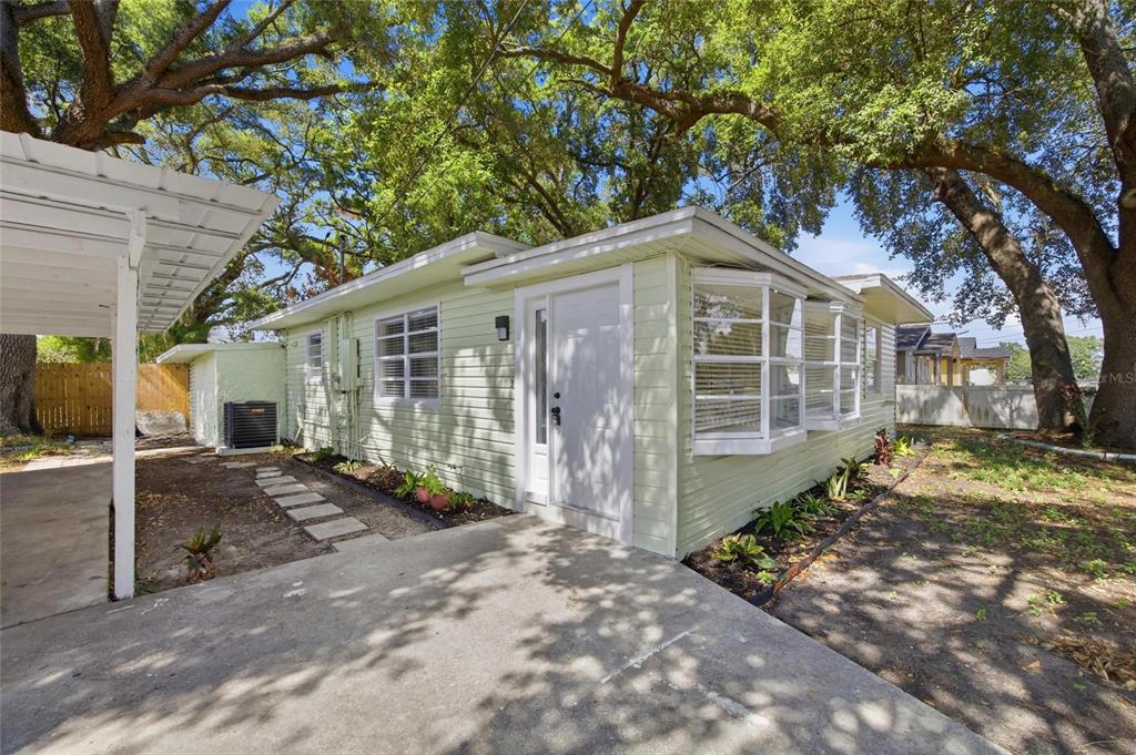 A light green house with a white door, bay windows, and a covered carport — 714 E 137TH AVENUE, TAMPA, FL