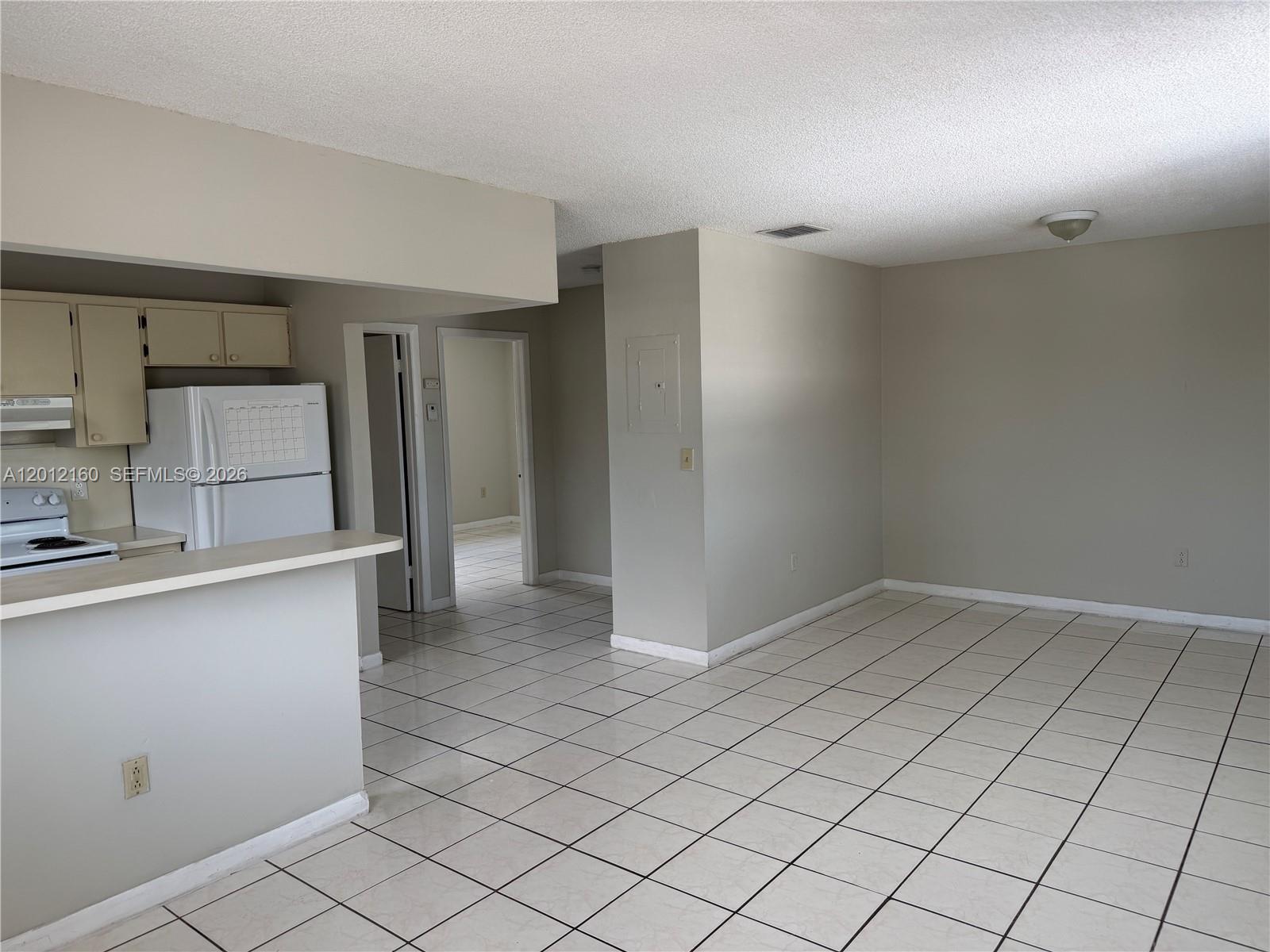 A kitchen with white appliances and a breakfast bar opens into a tiled living area — 837 SE 8th Ct # 2, Hialeah FL 33010, HIALEAH, FL