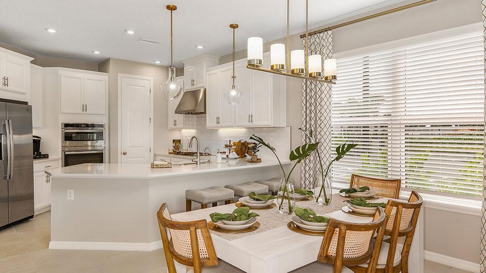 A kitchen with white cabinets and a dining area featuring a wooden table and chairs — 5641 GINGHAM DRIVE, KISSIMMEE, FL