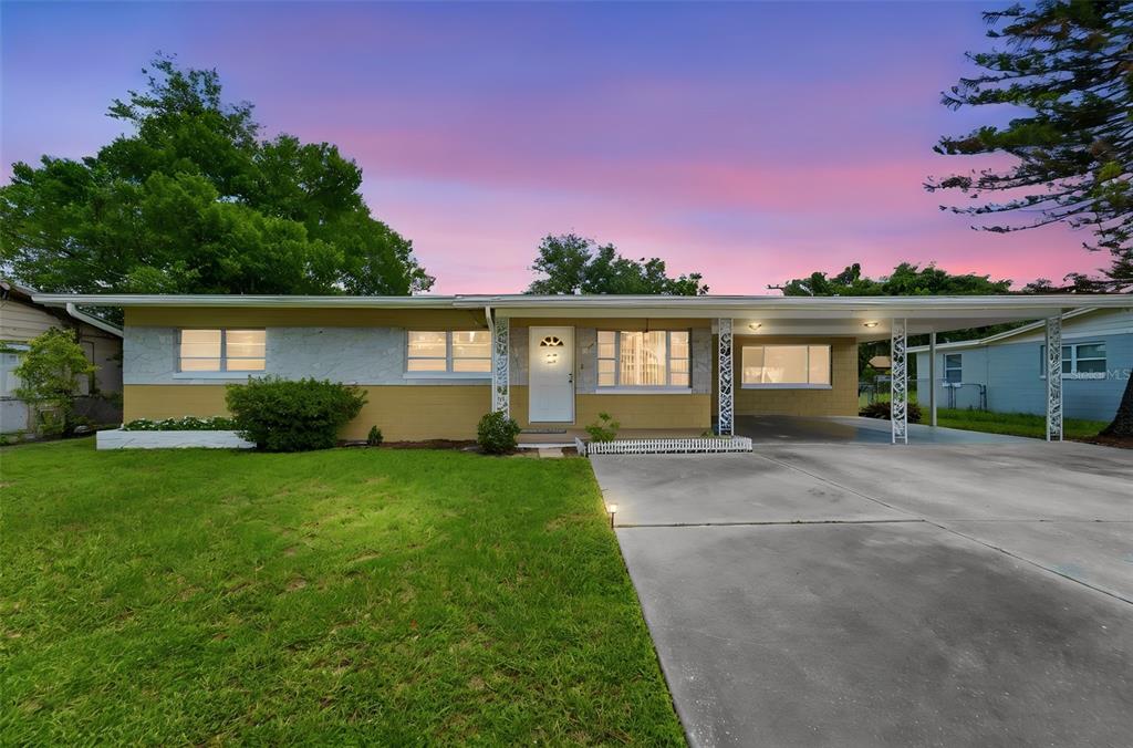 A single-story house with a yellow and gray exterior features a carport and front lawn — 123 E LAKE MARY DRIVE, ORLANDO, FL