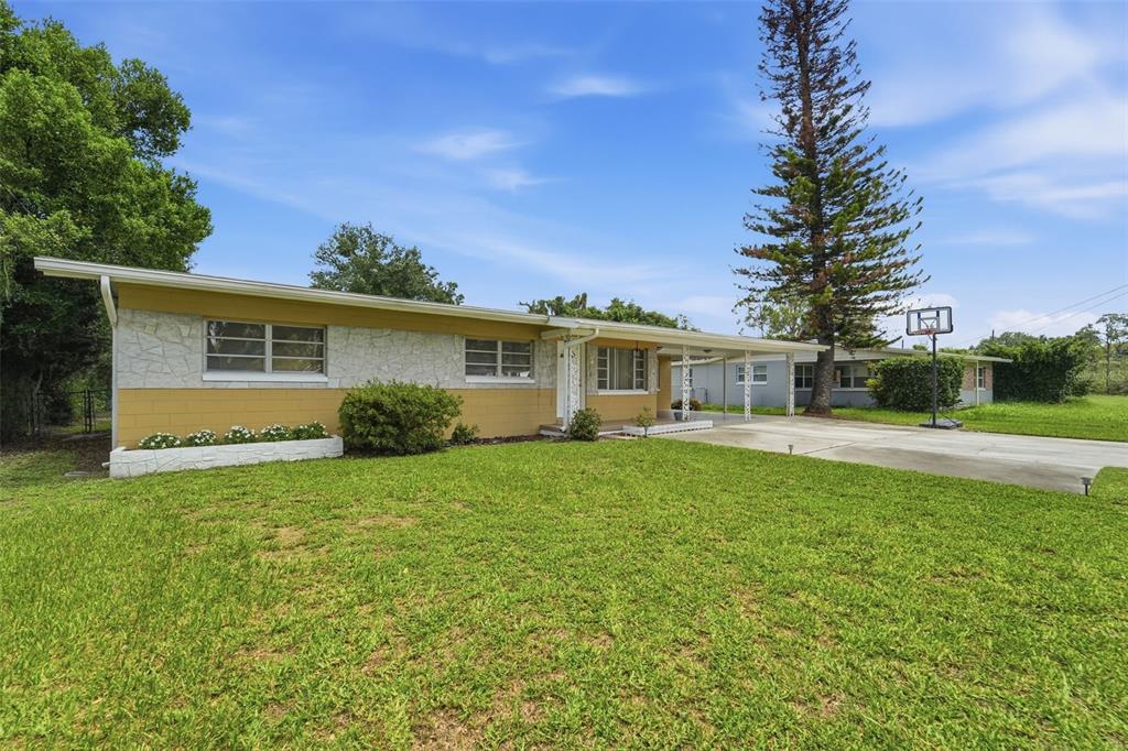 A single-story house with yellow and stone siding features a carport and a basketball hoop — 123 E LAKE MARY DRIVE, ORLANDO, FL