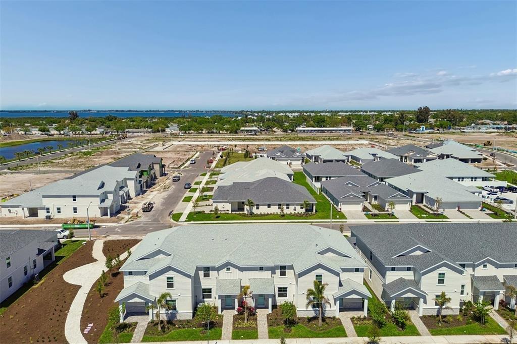 An aerial view shows a suburban neighborhood with newly constructed townhomes and houses under development — 8119 SEAFLOWER PARKWAY, BRADENTON, FL