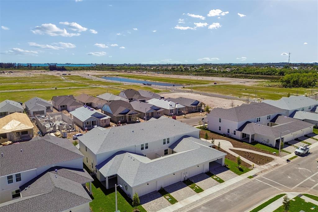 An aerial view shows a suburban neighborhood with newly constructed houses and surrounding undeveloped land — 8119 SEAFLOWER PARKWAY, BRADENTON, FL