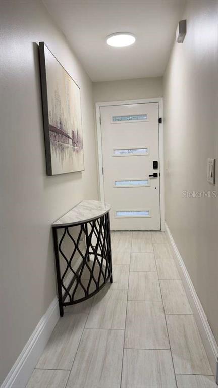 An entryway features a white door, a semi-circular console table, and light-colored tile flooring — 1420 MYRNA LANE, KISSIMMEE, FL