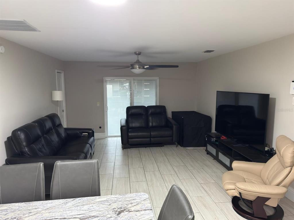 A living room features light tile flooring, a ceiling fan, black leather furniture, and a television — 1420 MYRNA LANE, KISSIMMEE, FL