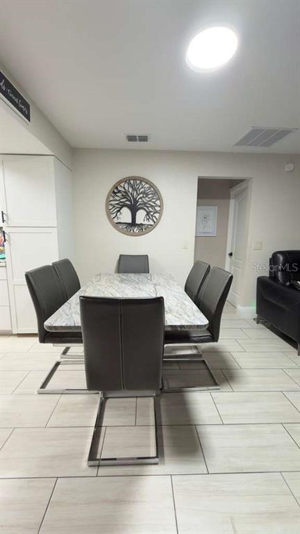 A dining area features a marble-topped table with six gray chairs on a tiled floor — 1420 MYRNA LANE, KISSIMMEE, FL