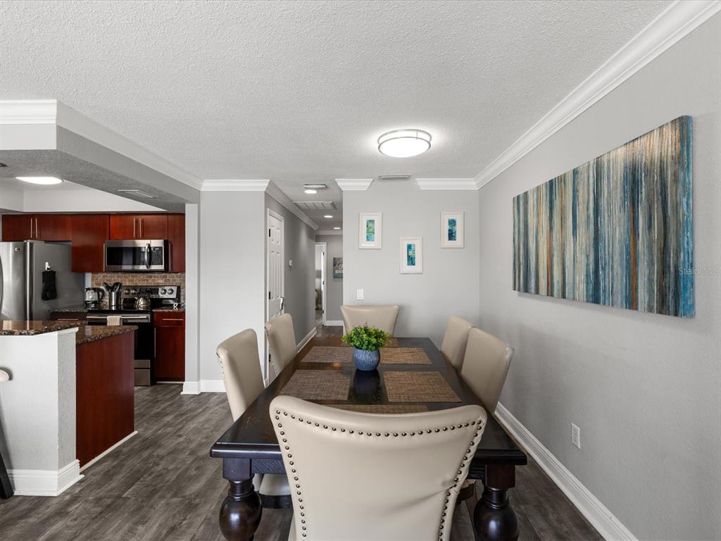 A dining area features a dark wood table with upholstered chairs and an adjacent kitchen — 185 BRIGHTWATER DRIVE UNIT 6, CLEARWATER BEACH, FL