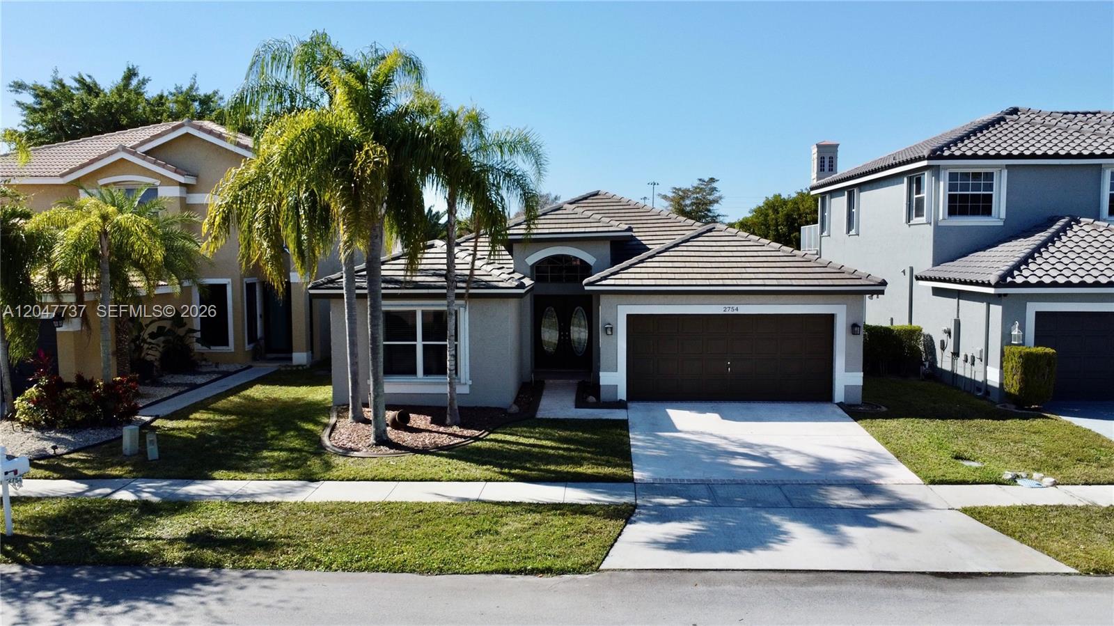 A single-story suburban house with a two-car garage, tile roof, and palm trees in front — 2754 SW 183rd Ave, Miramar FL 33029, MIRAMAR, FL