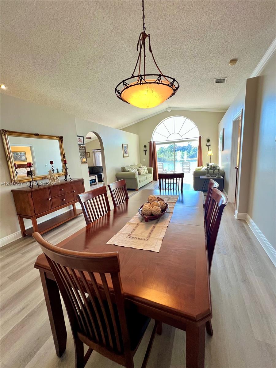 A dining room with a wooden table and chairs sits before a living area with lake views — 2754 SW 183rd Ave, Miramar FL 33029, MIRAMAR, FL