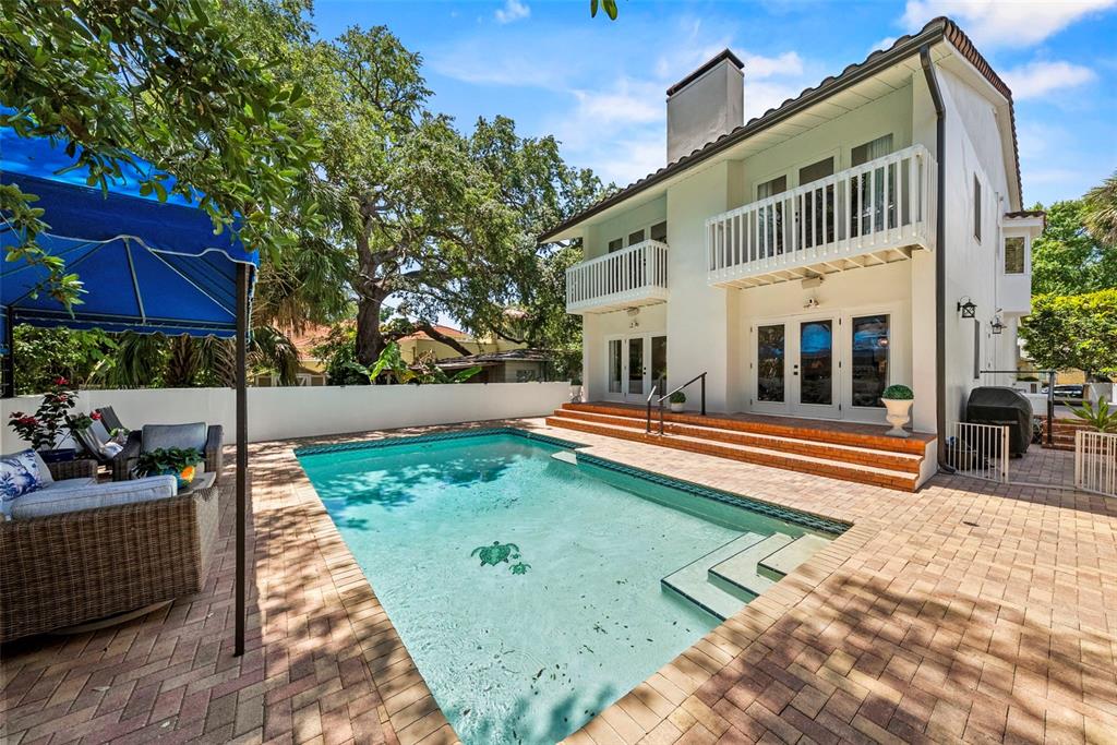 A two-story house with a balcony overlooks a backyard swimming pool and brick patio — 47 AEGEAN AVENUE, TAMPA, FL