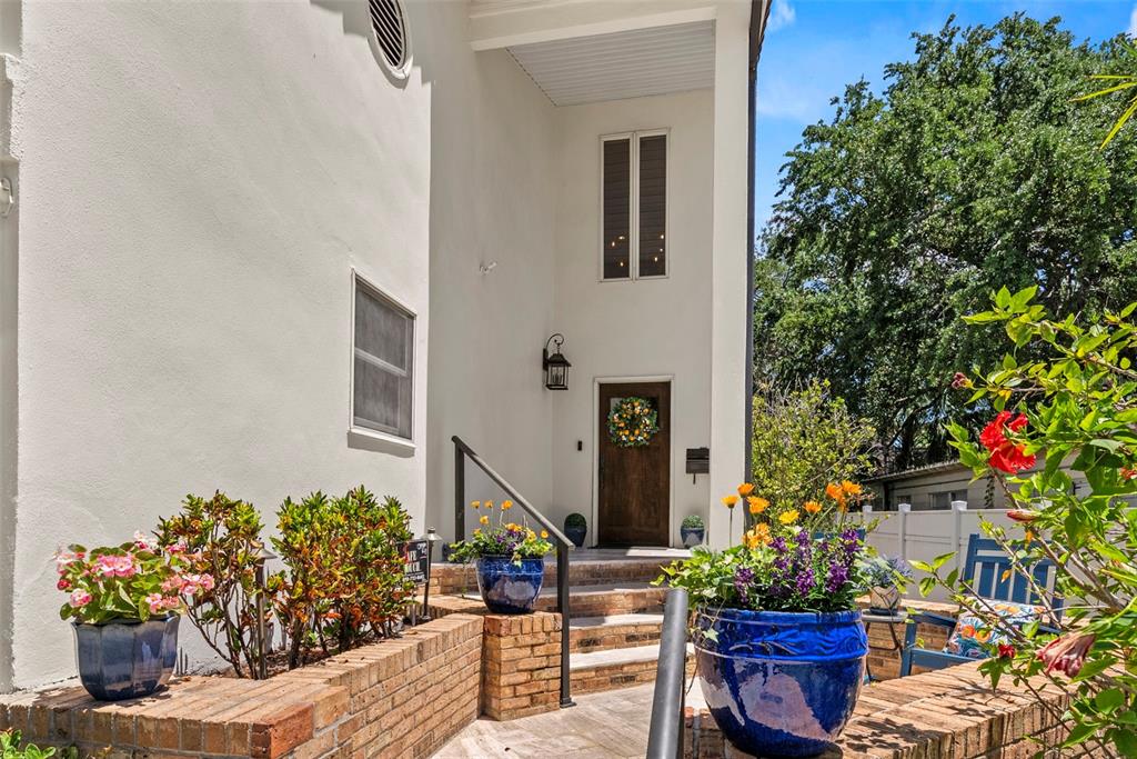 A front entrance with a wooden door, brick steps, and blue potted flowers — 47 AEGEAN AVENUE, TAMPA, FL