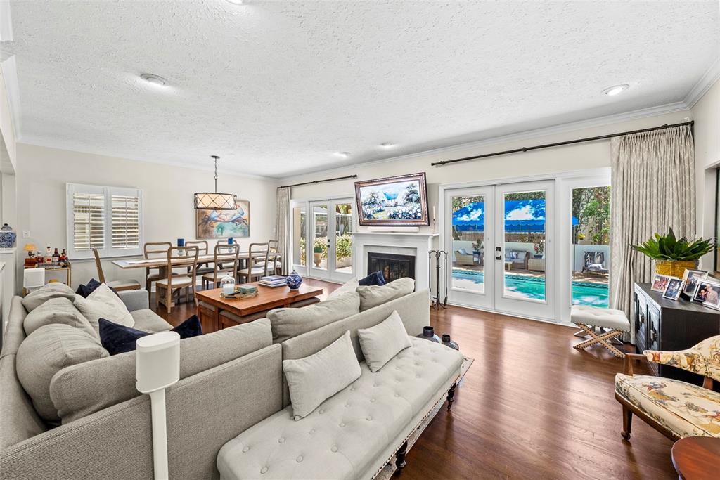 A living room with a fireplace, sectional sofa, dining area, and glass doors to a pool — 47 AEGEAN AVENUE, TAMPA, FL