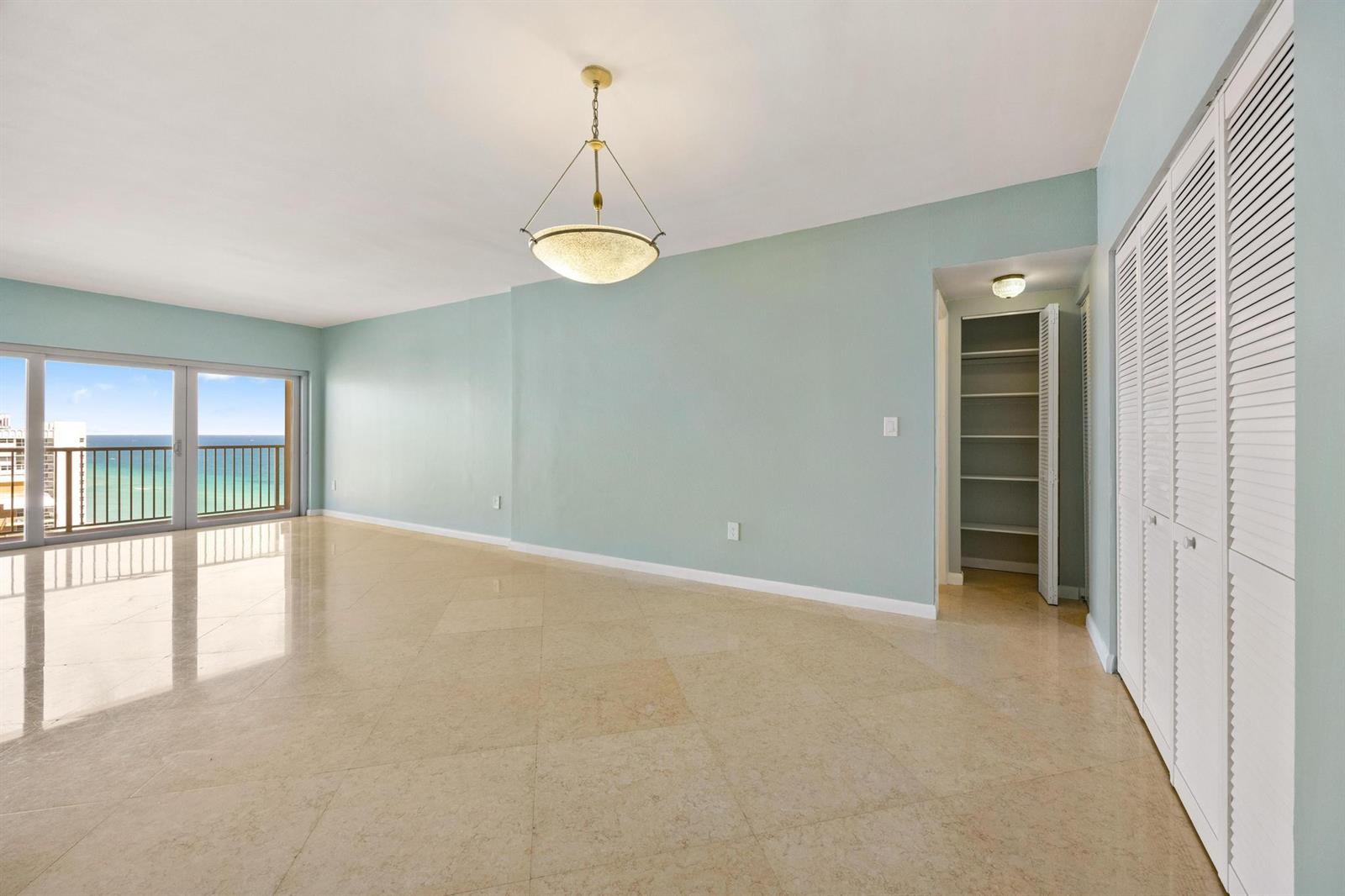 An empty room with light blue walls, beige tile floors, a chandelier, and balcony ocean views — 1950 S Ocean Drive, Hallandale Beach FL 33009, HALLANDALE BEACH, FL