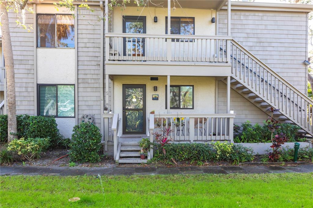 A two-story apartment building exterior with a ground-level porch, upper balcony, and wooden stairs — 1531 CLOWER CREEK DRIVE UNIT HA245, SARASOTA, FL