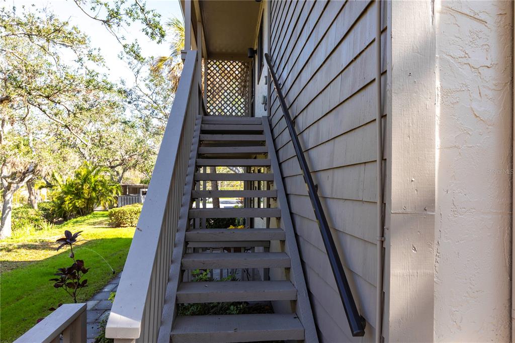 An exterior wooden staircase leads up to a covered landing beside a building — 1531 CLOWER CREEK DRIVE UNIT HA245, SARASOTA, FL