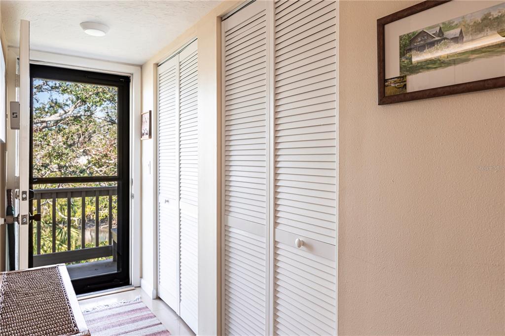 A hallway features louvered closet doors, a beige wall, and a door leading to a balcony — 1531 CLOWER CREEK DRIVE UNIT HA245, SARASOTA, FL