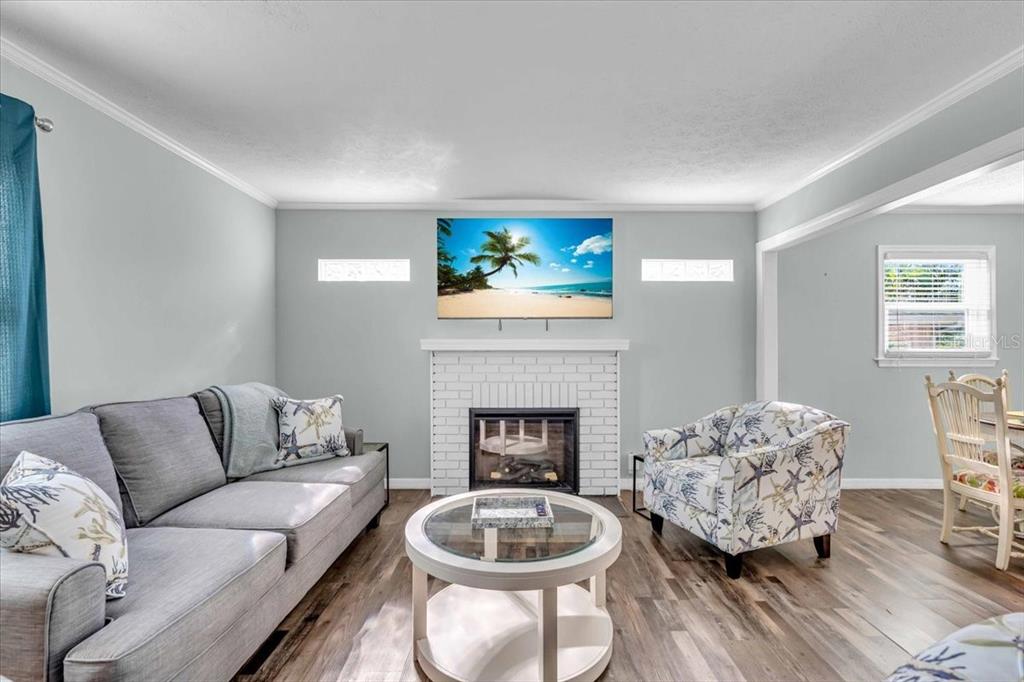 A living room features a white brick fireplace, a television, a sofa, and an armchair — 3843 CHAPEL DRIVE, SARASOTA, FL