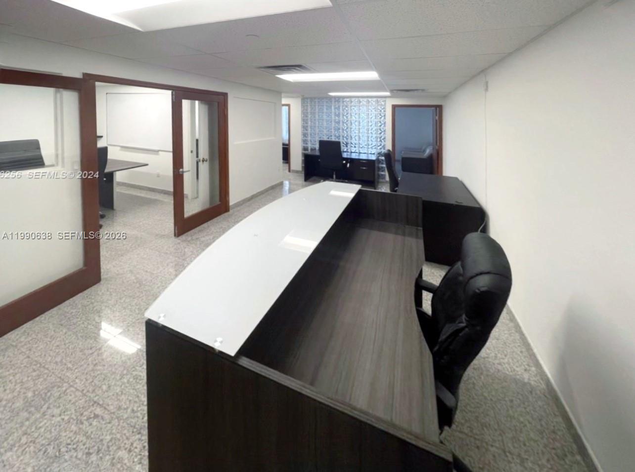 An office reception area features a modern desk, glass-paneled doors, and a glass block wall — 4300 Biscayne Blvd # 202, Miami FL 33137, MIAMI, FL