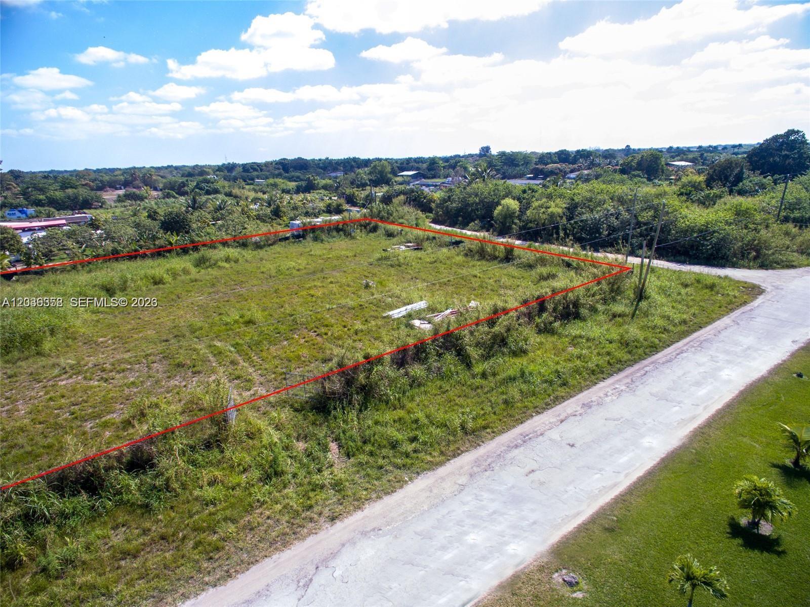An aerial view shows a vacant, grass-covered rectangular lot outlined in red next to a road — 21151 SW 160, Miami FL 33187, MIAMI, FL