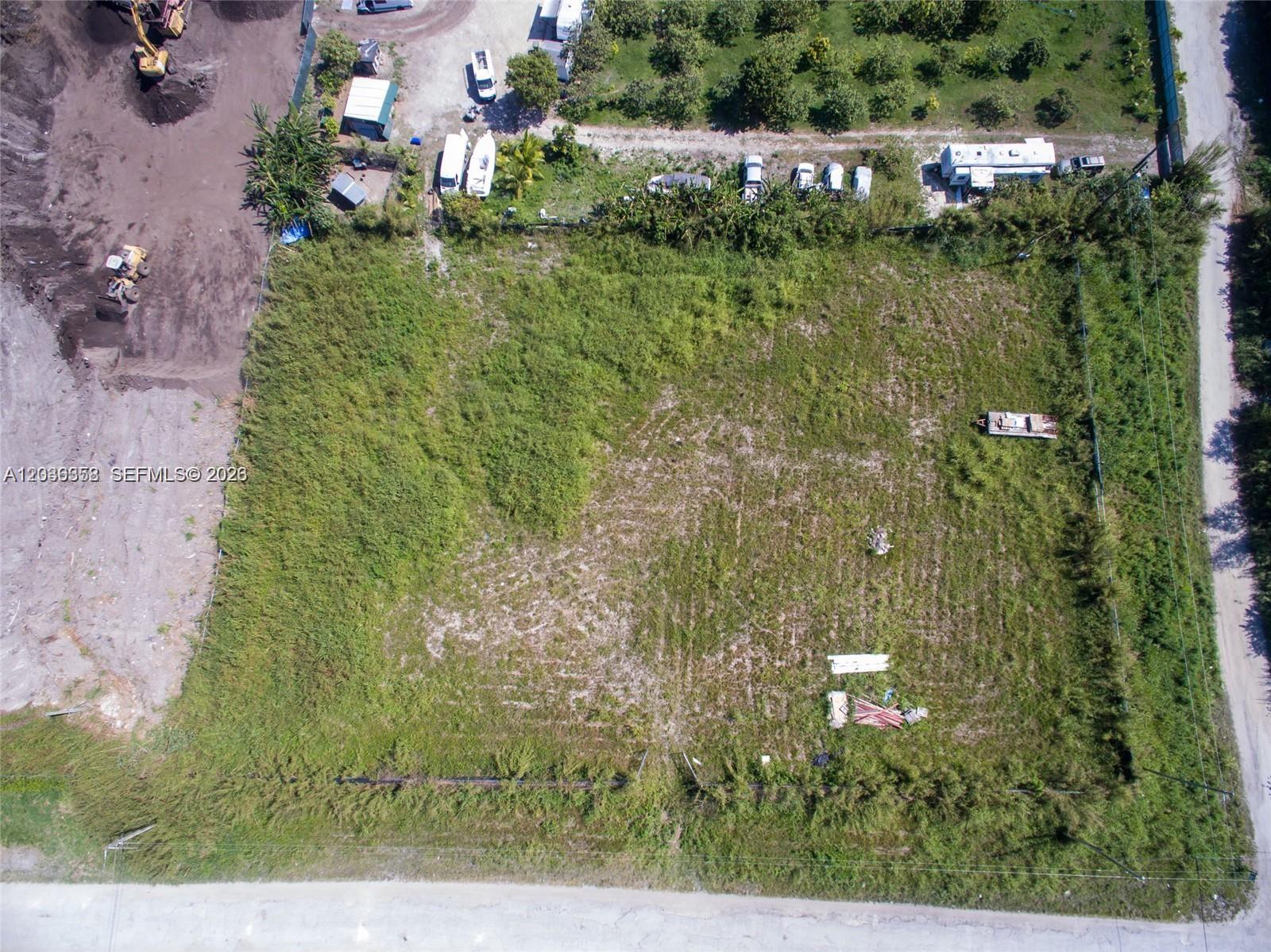 An aerial view shows a rectangular, grass-covered vacant lot bordered by a road and trees — 21151 SW 160, Miami FL 33187, MIAMI, FL