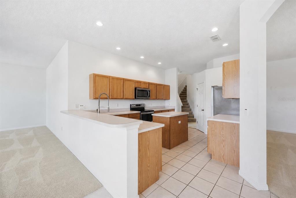 An empty dining room with beige carpet, white walls, and a chandelier over the window — 458 BLOOMINGDALE DRIVE, DAVENPORT, FL
