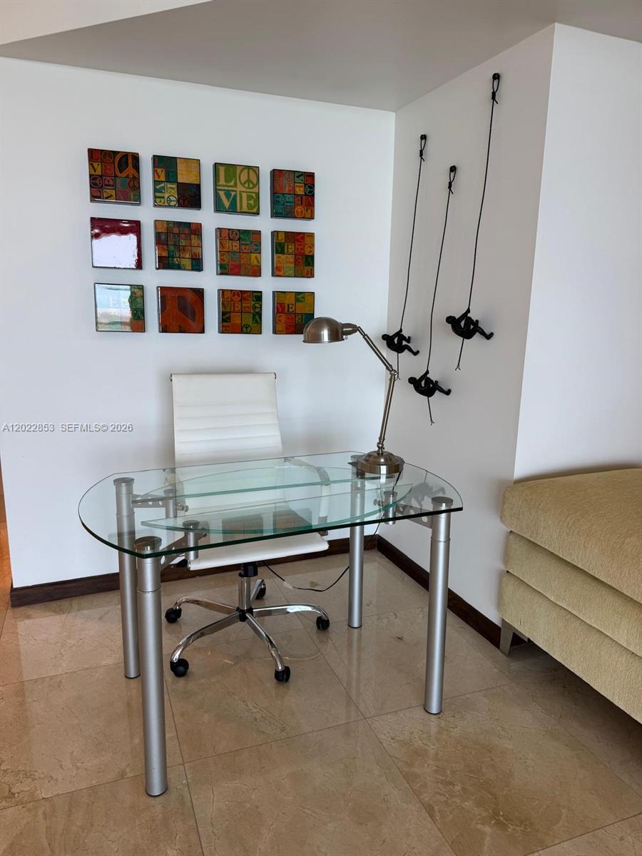 A home office area features a glass desk, white chair, wall art, and climbing figure decor — 450 Alton Rd # 3505, Miami Beach FL 33139, MIAMI BEACH, FL