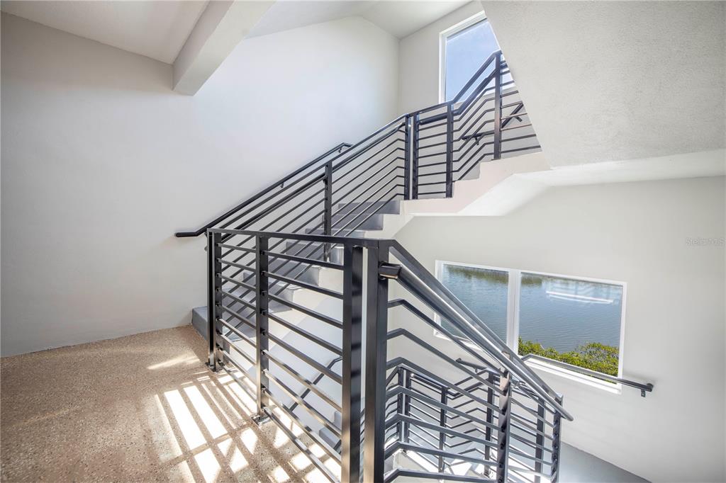 A staircase with black metal railings and concrete steps leads to an upper landing — 19505 GULF BOULEVARD UNIT 304, INDIAN SHORES, FL