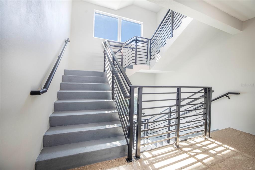 A staircase with gray concrete steps and black metal railings leads to a landing — 19505 GULF BOULEVARD UNIT 304, INDIAN SHORES, FL