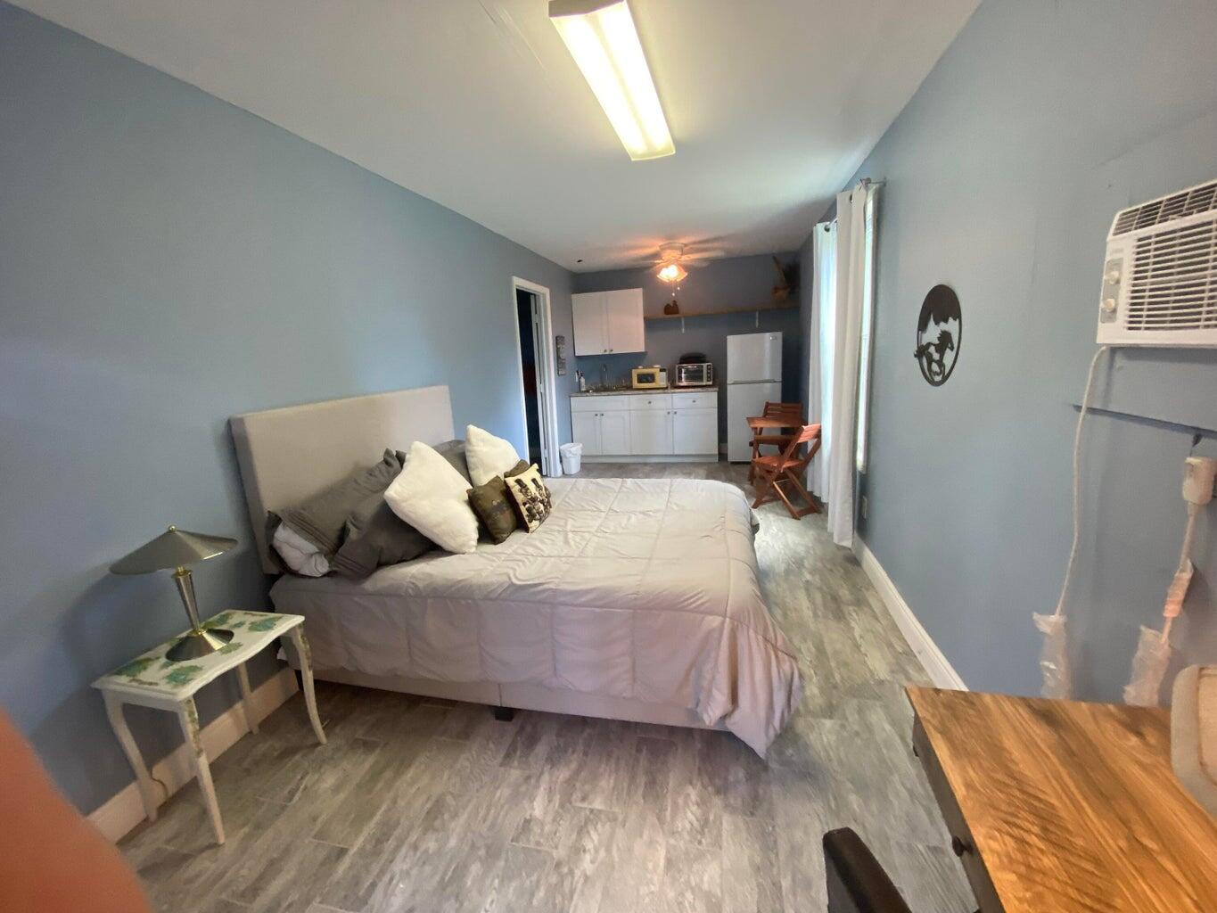 A bedroom with a kitchenette, light blue walls, wood-look flooring, and a queen-sized bed — 2141 B Road, FL 33470, FL