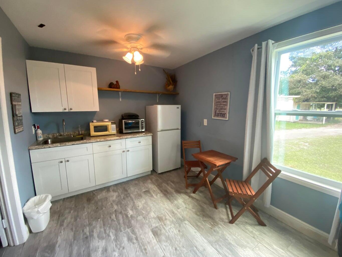 A small kitchen with white cabinets, a refrigerator, a microwave, and a wooden dining set — 2141 B Road, FL 33470, FL