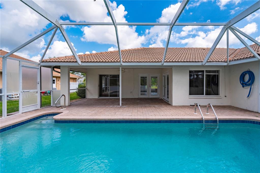 A screened-in patio with a swimming pool and a tiled roof house exterior — 27055 CHILE DRIVE, PUNTA GORDA, FL