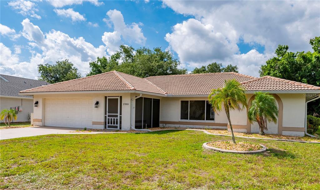 A single-story house with a tiled roof, a two-car garage, and a front screen door — 27055 CHILE DRIVE, PUNTA GORDA, FL