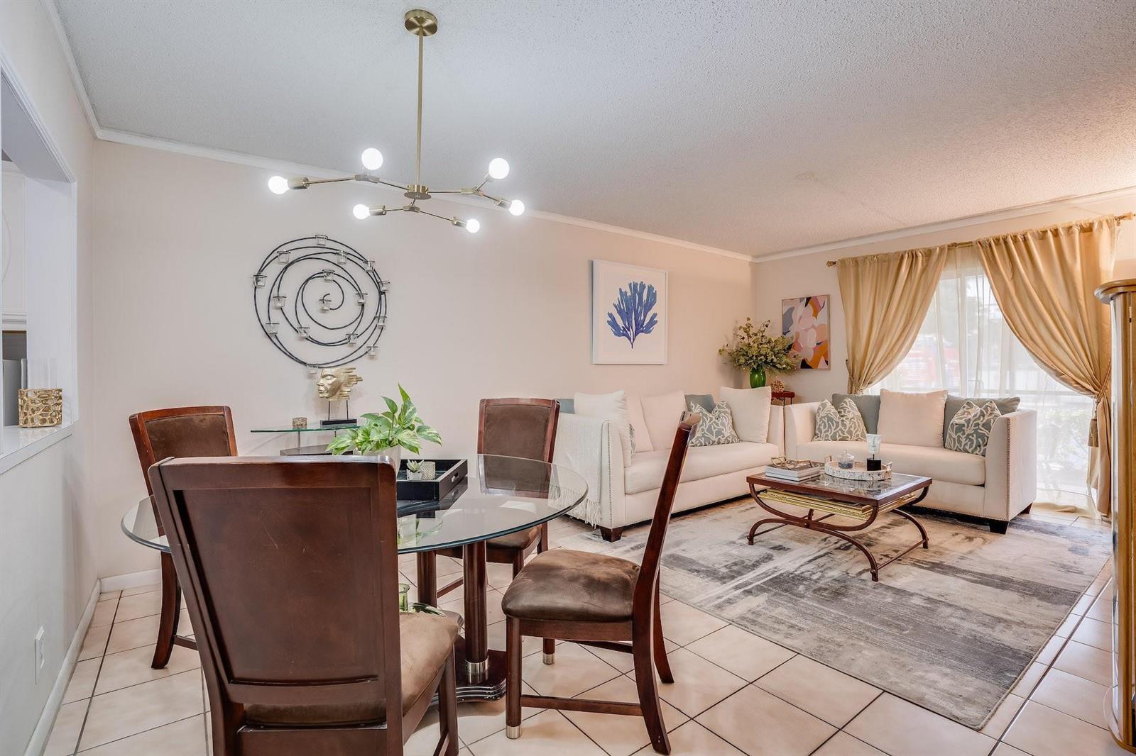 A dining area with a glass table and a living room with white sofas — 253 S Cypress Road # 202, Pompano Beach FL 33060, POMPANO BEACH, FL