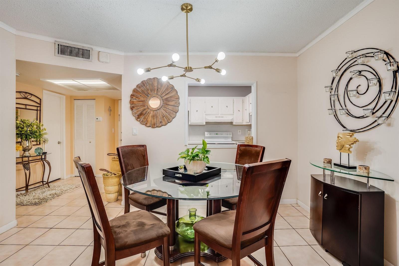 A dining room with a glass-topped table, four brown chairs, and a modern chandelier — 253 S Cypress Road # 202, Pompano Beach FL 33060, POMPANO BEACH, FL