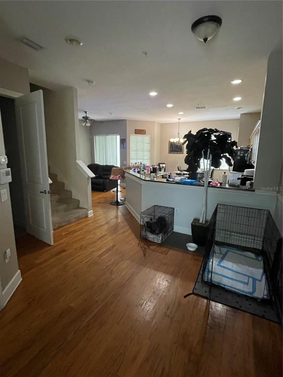 An open-concept living area features hardwood floors, a kitchen island, and a staircase — 8405 COSTA BELLA WAY, TEMPLE TERRACE, FL