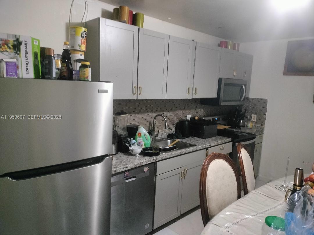 A kitchen features gray cabinets, stainless steel appliances, and a granite countertop — 3206 SW 47th Ave, West Park FL 33023, WEST PARK, FL